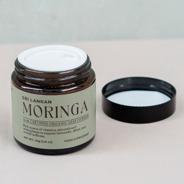 A glass jar of Sri Lankan moringa leaf powder with the lid off, showing the protective inner lid designed to keep the powder secure and fresh.