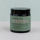 A glass jar of Sri Lankan ceremonial-grade matcha with a black lid, featuring a green label and subtle pink text for a clean, minimalistic look with Nature's Antidote branding.